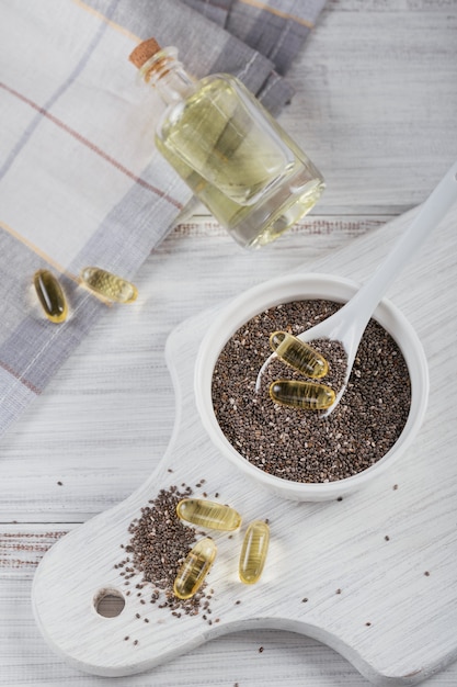 Chiazaad in een kleine kom en gelatine capsules met omega-olie op een witte houten achtergrond.