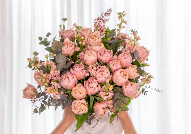 写真 白い背景の女性の手でピンクのチューリップの麗な花束