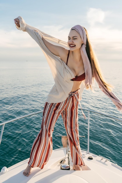 Chic happy girl in fashionable clothes enjoys a holiday on a yacht sails on the Caribbean sea