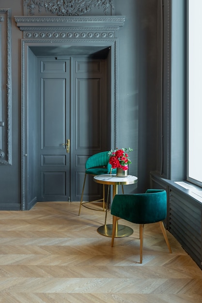 Chic interior of the room in the Renaissance style of the 19th century with modern luxury furniture. walls of noble dark color are decorated with stucco and gilded frames, wooden parquet.