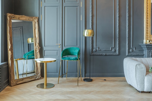 Chic interior of the room in the Renaissance style of the 19th century with modern luxury furniture. walls of noble dark color are decorated with stucco and gilded frames, wooden parquet.