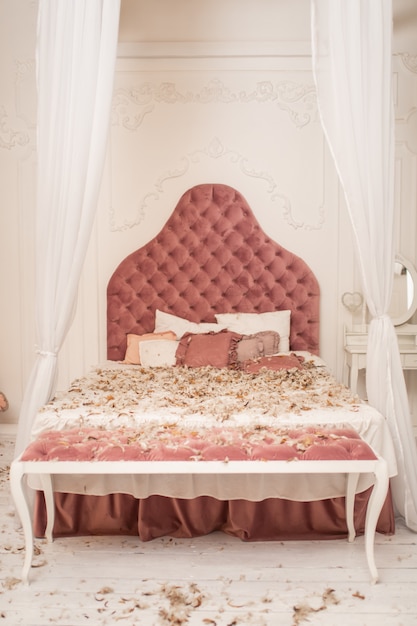 枕から羽が散らばったシックなレトロなキングサイズのベッド、部屋で枕の戦い。