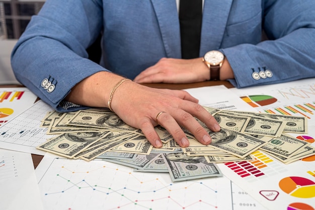 Chic young male businessman calculates his business graphs at the office desk