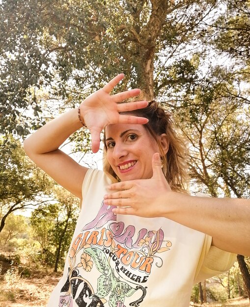 Photo chica joven en el bosque enmarcándose la cara con las manos