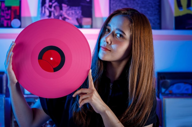 Photo chica latina sosteniendo un disco de vinilo en sus manos concepto de chica dj en tienda de discos