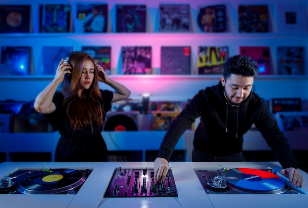 Chica y chico dj mezclando msica en una tienda de discos de vinilo usando un tornamesa retro