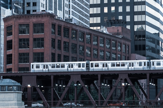 Photo chicago : october 10, 2018, train on elevated tracks within buildings at the loop, glass and steel bridge between buildings - chicago city center - chicago, illinois, usa