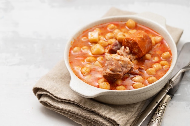 Chick pea with smoked sausages in white bowl