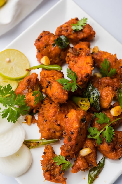 Chicken 65  spicy deep fried Bar appetizer or quick snack from India in a bowl or plate over white