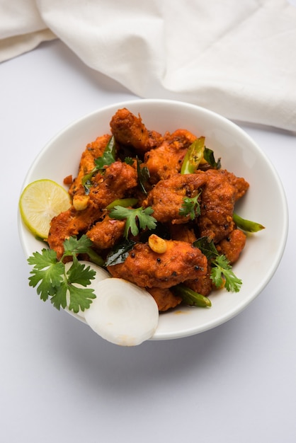 Chicken 65  spicy deep fried Bar appetizer or quick snack from India in a bowl or plate over white