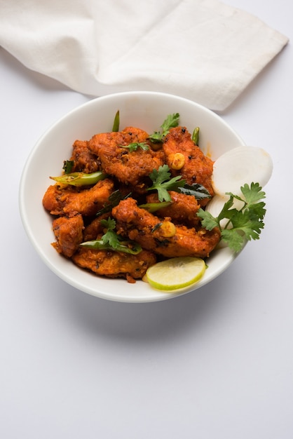 Chicken 65  spicy deep fried Bar appetizer or quick snack from India in a bowl or plate over white