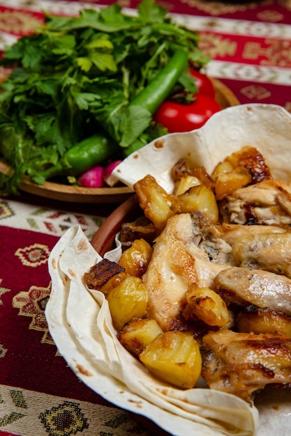 Chicken baked in pieces with potatoes and onion on a clay plate