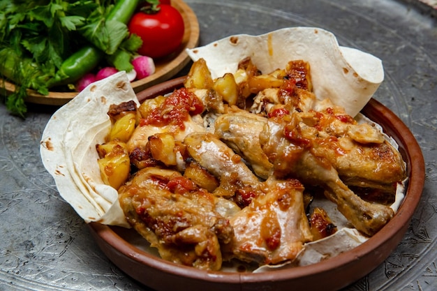 Chicken baked in pieces with potatoes and onion on a clay plate