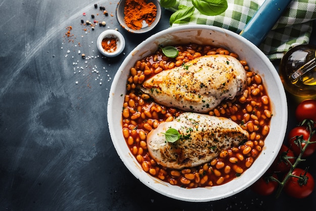 Chicken breast cooked or stuffed with beans in tomato sauce on pan.