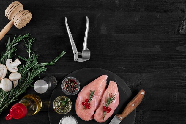 Chicken breast on a cutting board with herbs and different vegetables on rustic wooden background Top view Copy space Still life Flat lay