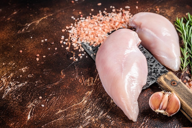 Filetto di petto di pollo carne di pollame cruda fresca su mannaia da macellaio sfondo in legno scuro vista dall'alto spazio di copia