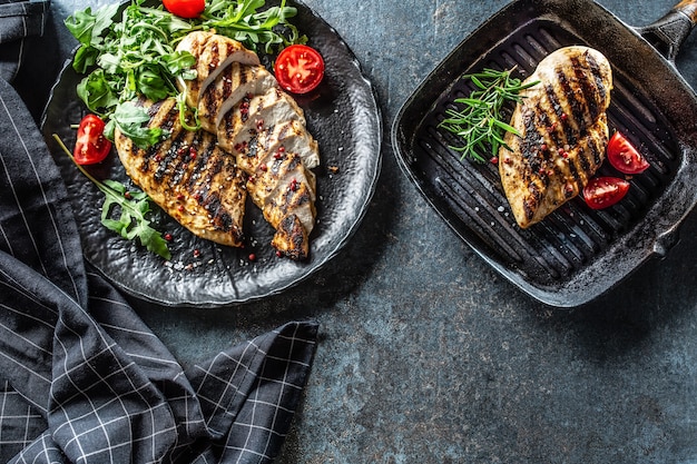 Petto di pollo alla griglia con spezie pepe sale pomodori rosmarino e rucola - vista dall'alto.