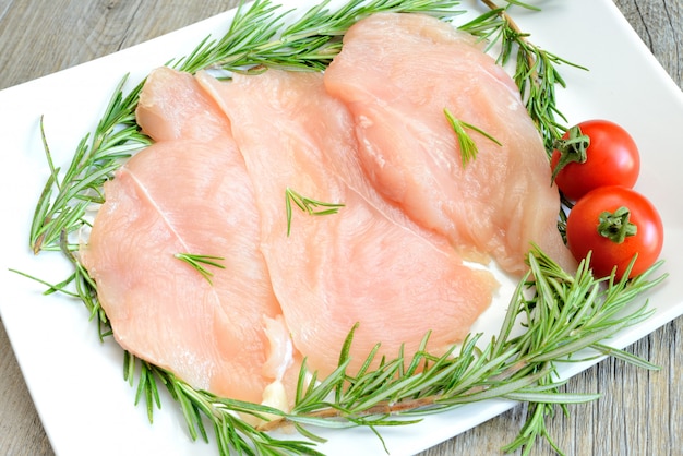 Chicken breast and rosemary on plastic dish