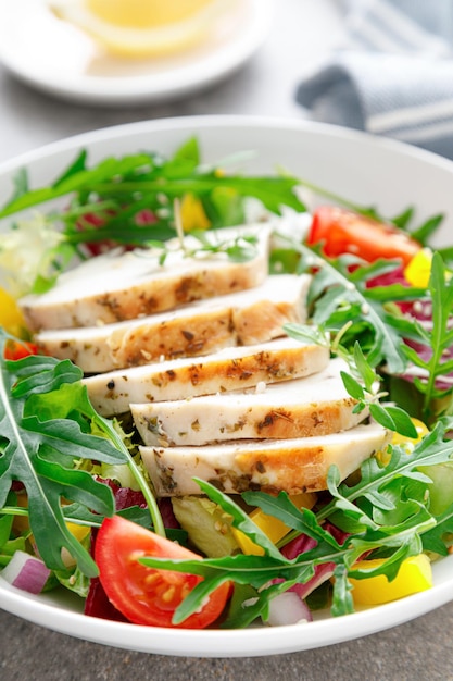 Chicken breast salad Fresh vegetable salad with tomato pepper arugula and grilled chicken breast in bowl healthy food