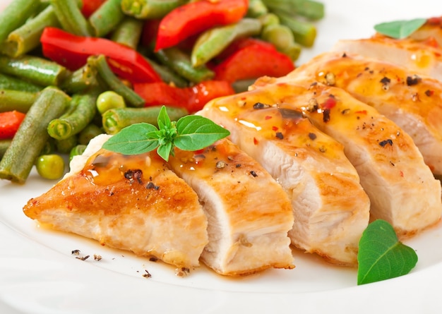 Chicken breast with vegetables and sauce decorated with basil leaves