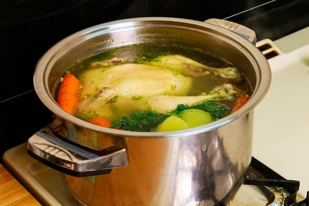 Chicken broth carrots chicken green Chicken soup in a bowl with crackers.