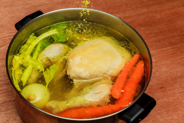 Chicken broth carrots chicken green Chicken soup in a bowl with crackers.