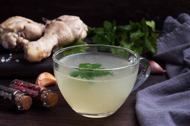 Chicken broth in a glass Cup. Boiled chicken leg quarters.