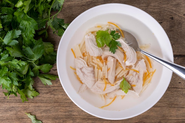 Chicken broth in a white plate on a wooden background