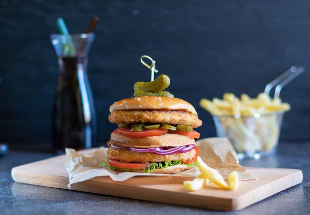 暗い背景にチキンバーガーとフライドポテトとコカコーラのボトル