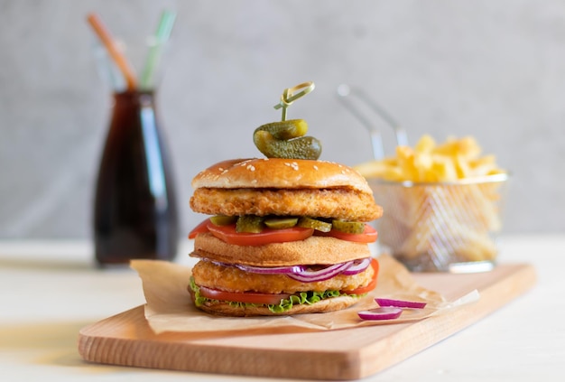 Chicken burger with fries and a bottle of cocacola on a light background