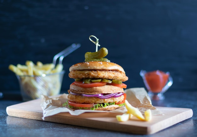 暗い背景にフライドポテトとケチャップを添えたチキンバーガー