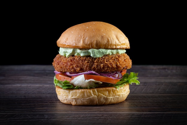 Chicken burger with lettuce, tomato, purpple onion and handmade mayo on the wood table. Delicious.