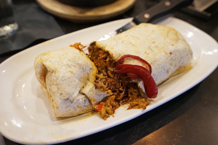 Фотография куриное бурито мексиканской и текс-мексиканской кухни состоит из мучной тортильи