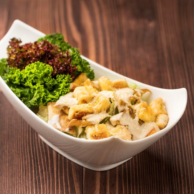 Chicken ceaser salad with chicken breast cubes and salad leaves served in dish isolated on table top view green food