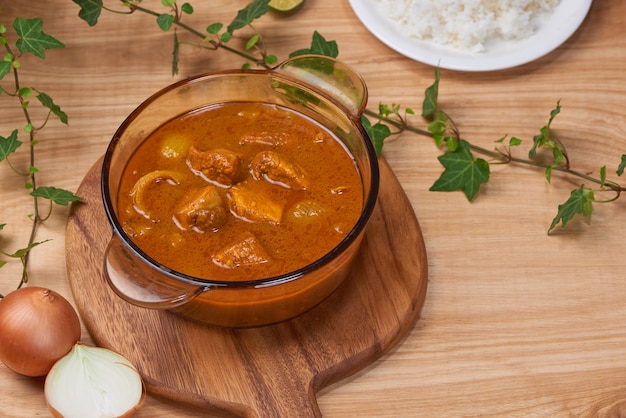 木製の背景に鍋にスパイスとチキンカレー