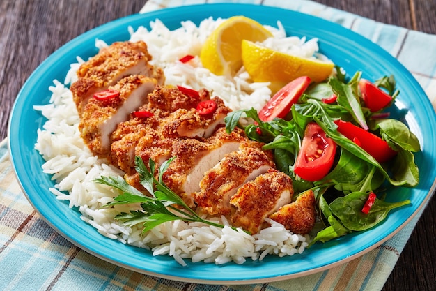 Chicken Cutlet Rice Bowl served with spinach tomato salad, horizontal view from above,close-up
