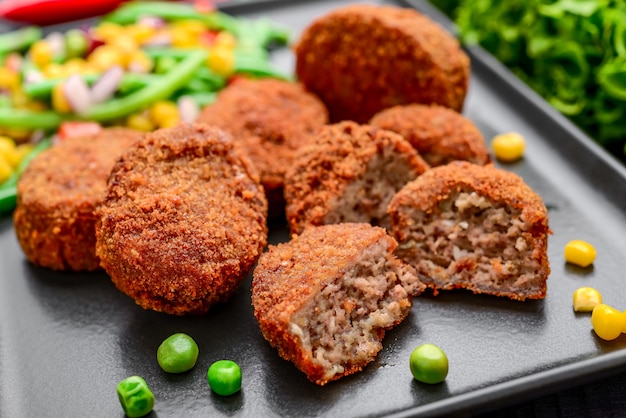 Chicken cutlets in batter with risotto and vegetables, on a black surface