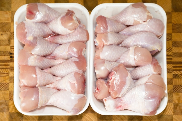 Cosce di pollo congelate in un contenitore su un tagliere di legno