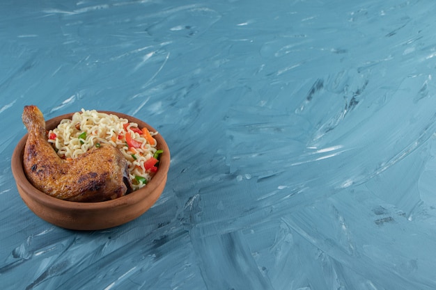 Chicken drumsticks and noodle in a bowl, on the marble background. 