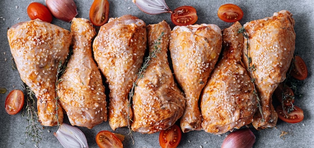 Chicken drumsticks with spices paprika and sesame seeds ready to bake on a baking sheet