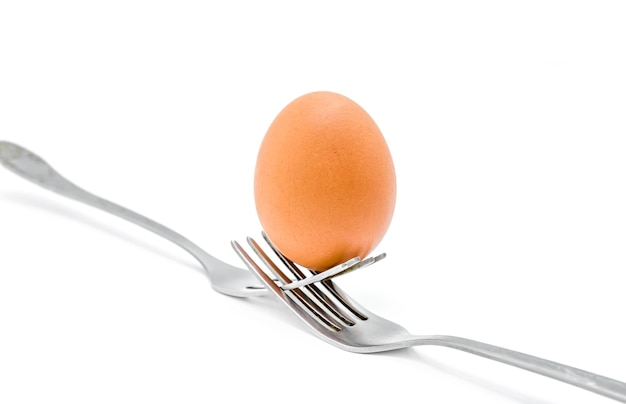 Photo chicken egg on metal forks isolated on white background closeup