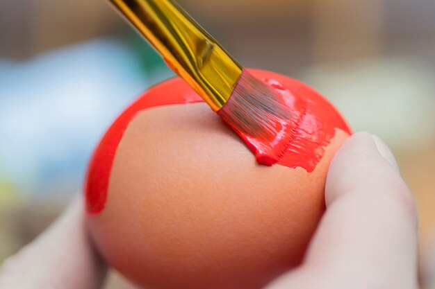 Chicken egg paint with a brush in red