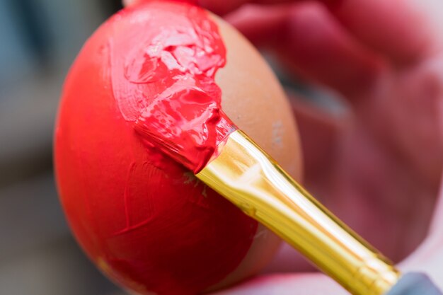 Chicken egg paint with a brush in red