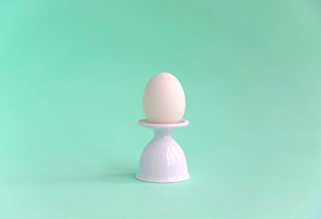 Chicken egg in a white egg stand.