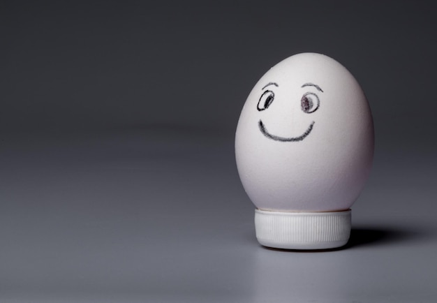 Uovo di gallina con una faccina sorridente su sfondo bianco neutro