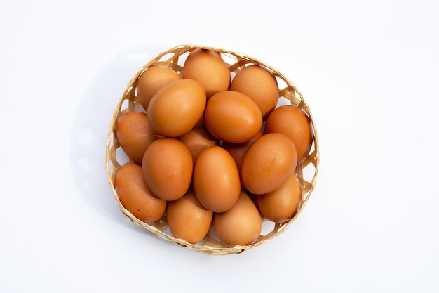 Chicken eggs in bamboo basket on white.