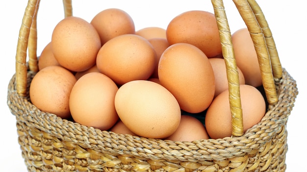 Chicken eggs in a basket on white background.