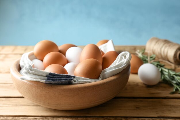Chicken eggs in bowl on wooden table