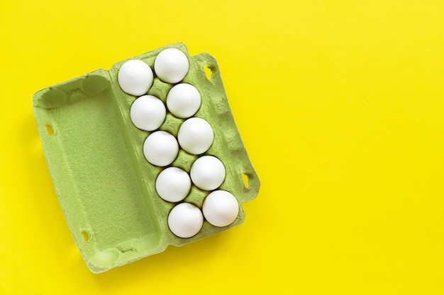 Chicken eggs in cardboard box on yellow paper background