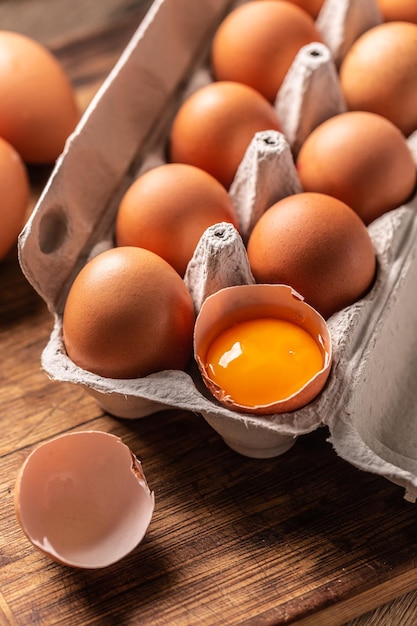 Chicken eggs in a cardboard box and yolk in shell.